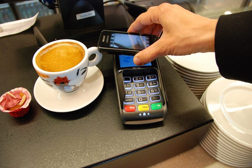 A smartphone lying on a glass table, its screen showing an account app with billing and pay bill tiles