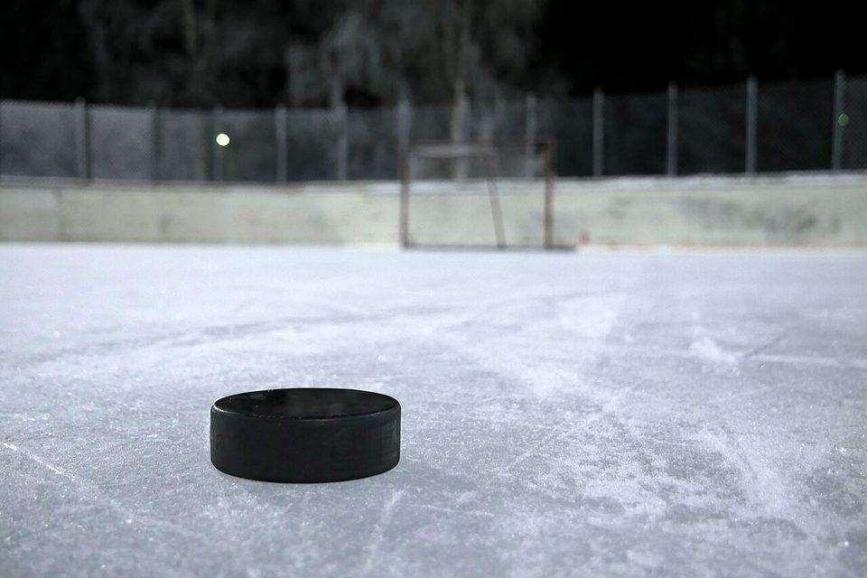A black ice hockey puck lying on scratched rink ice